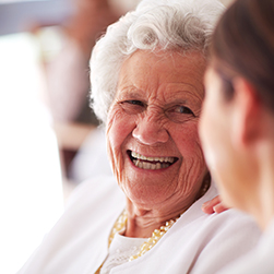 image of a female senior smiling towards a female caregiver.